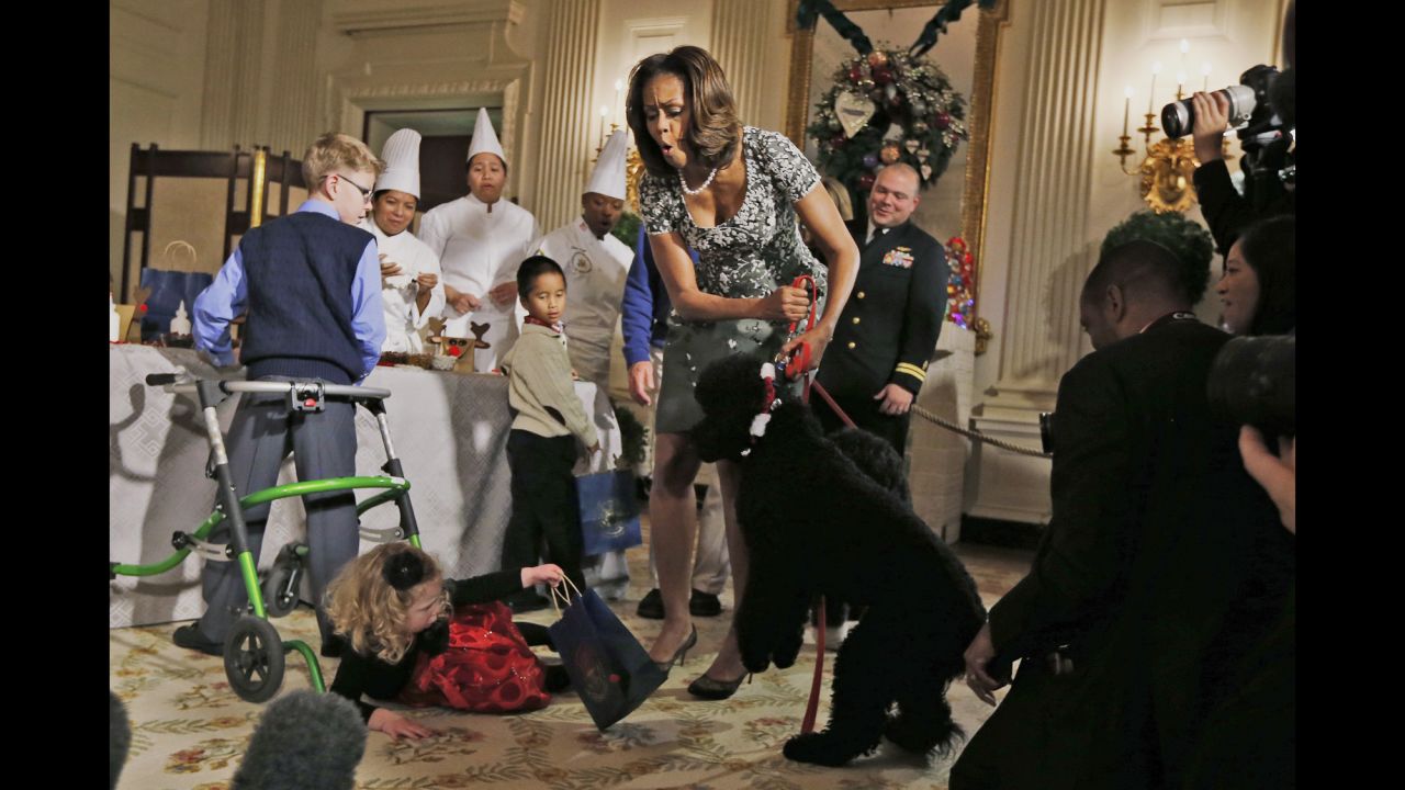 <strong>December 4:</strong> First lady Michelle Obama reacts as 2-year-old Ashtyn Gardner loses her balance after greeting Sunny, one of the Obamas' dogs, during a holiday arts-and-crafts event at the White House.