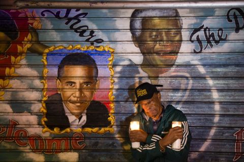 An artist who goes by the name Franco the Great stands beneath a Mandela mural that he painted in New York's Harlem neighborhood more than 15 years ago. He later added Obama to the mural.
