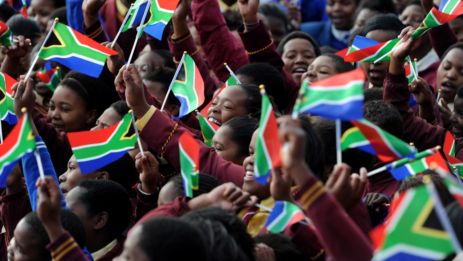 School kids from the Milton Mbekela school in South Africa wave flags.
