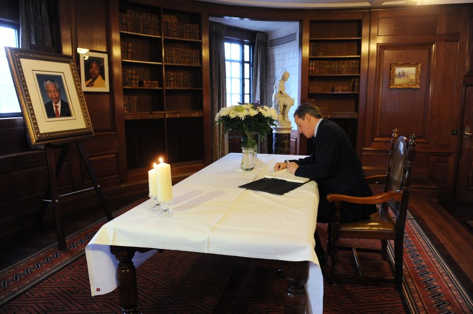 British Prime Minister David Cameron signs the book of condolence at the South African Embassy in central London following the announcement of Mandela's death.