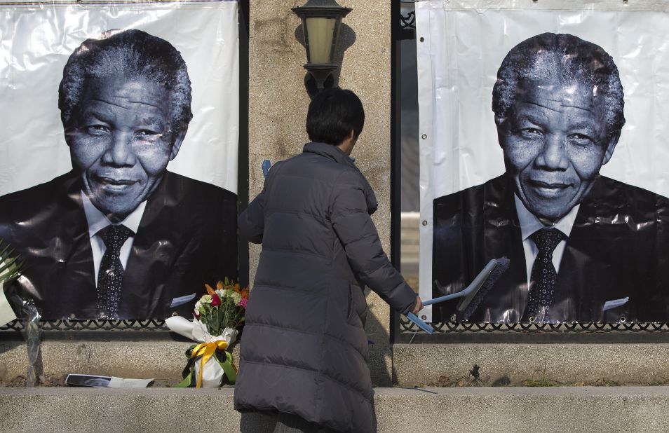 A woman cleans up outside the South African Embassy in Beijing where portraits of Mandela and flowers offered by people are placed on December 6.