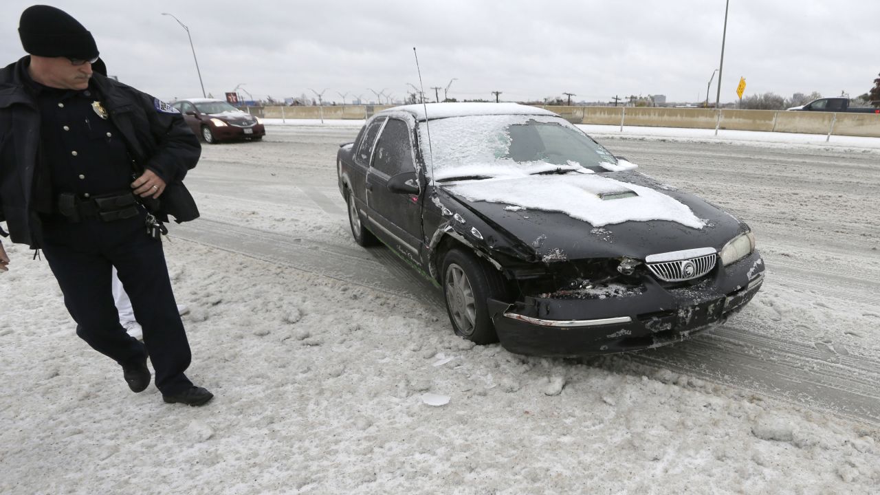 Un oficial de la policía revisa un auto dañado en un accidente a causa del hielo en un paso a desnivel de una carretera en Richardson, Texas, el 6 de diciembre.