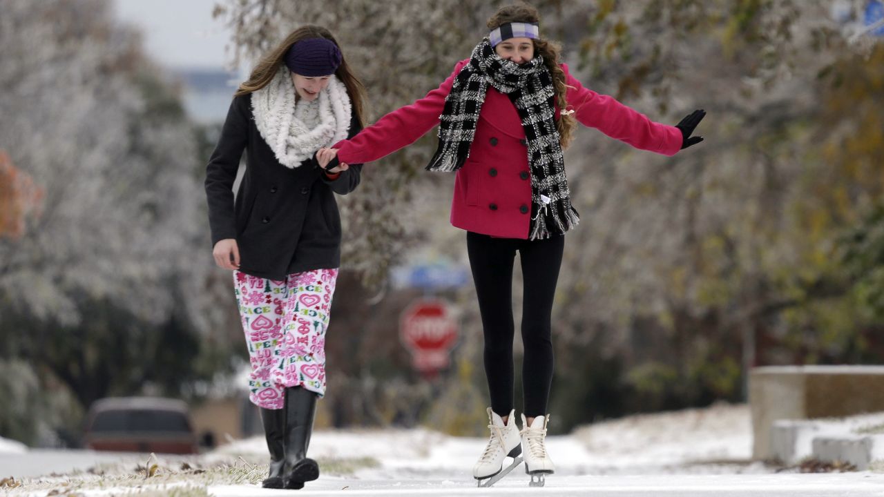 Jane Giles, de 15 años, a la derecha, es ayudada por su hermana Sarah Giles, de 17 años, mientras patona sobre una acera cubierta de hielo en Richardson, Texas, el 6 de diciembre.