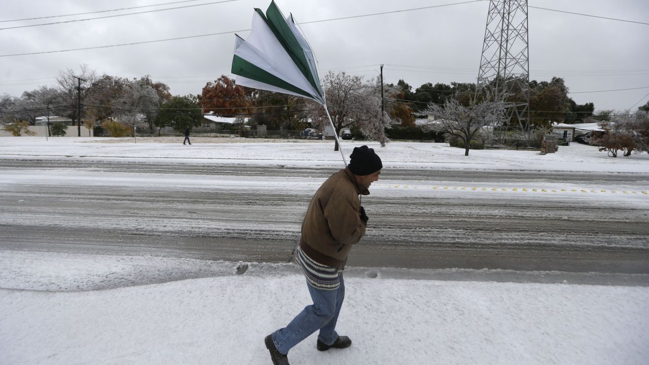 A gust of wind collapses Joseph Mezo's umbrella as he walks to work on December 6 in light sleet and ice conditions in Dallas.  