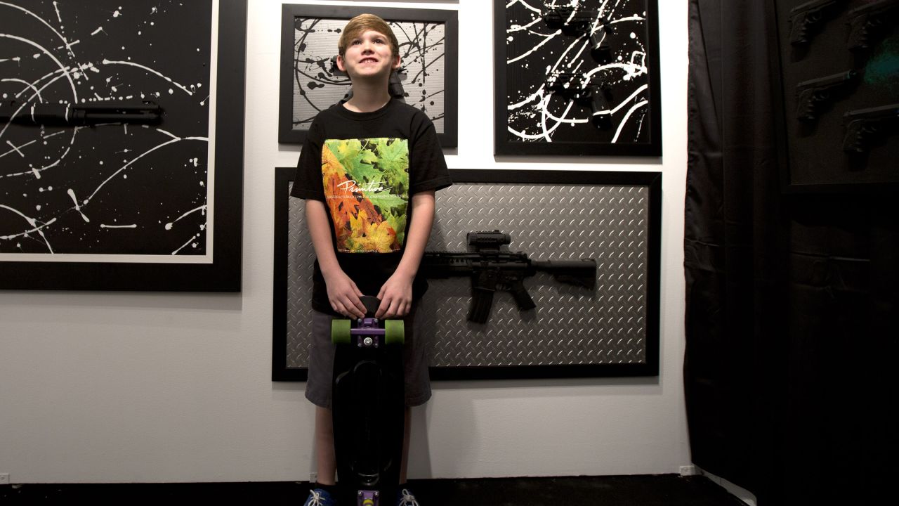 Charles Gitnick poses with his artwork during his Art Basel show in Miami, December 4. The 11-year-old is one of the youngest artists showing at Art Basel. Gitnick places realistic toy guns on canvas and paints over them, purposely camouflaging them in an abstract design. He says it's his way to express his fear of gun violence.