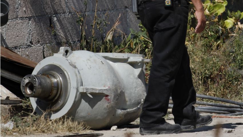 A firefighter stands next to the radiation head that was part of a radiation therapy machine, in the patio of the family who found the abandoned radiation head in a nearby field in the village of Hueypoxtla, Mexico, Thursday, Dec. 5, 2013.