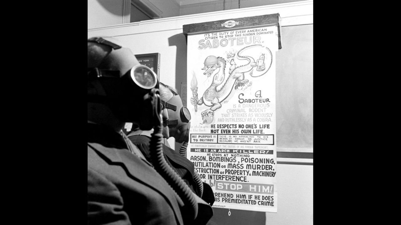 People stand next to a poster warning of the enemy at the Brooklyn Navy Yard in December 1941.