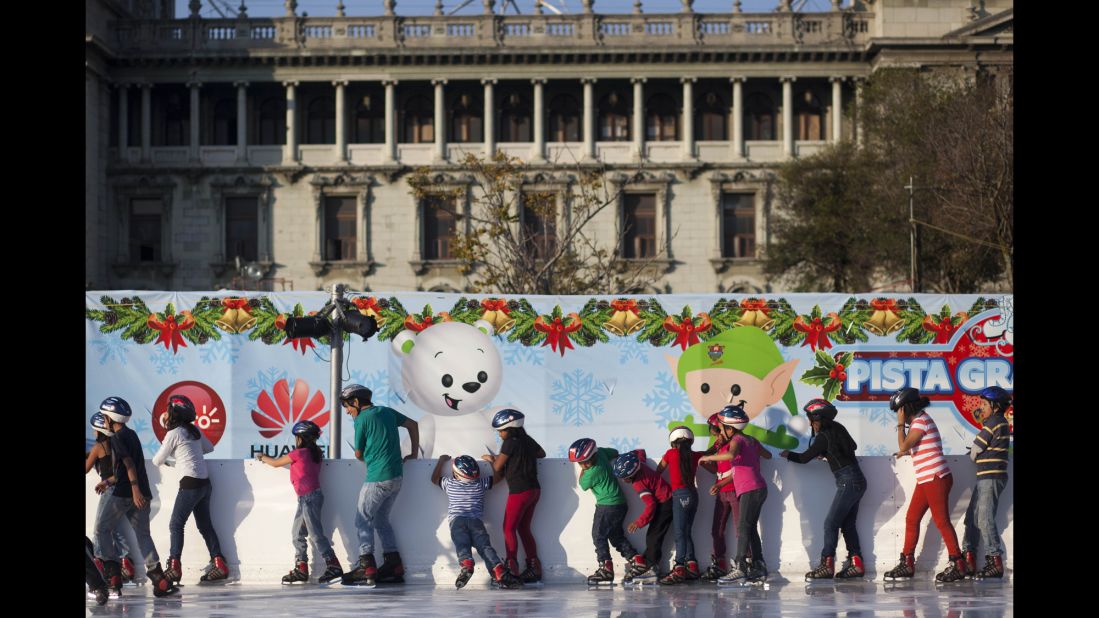 Young skaters in Guatemala City, Guatemala, hold on to a wall as they skate on an ice ring installed at Constitution Square on December 4.