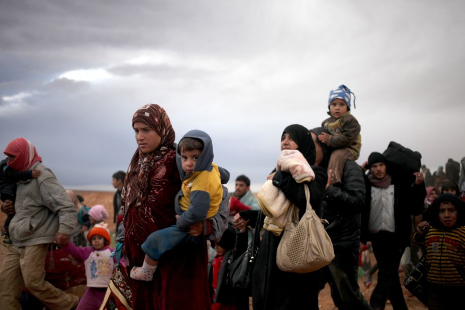 Newly arrived Syrian refugees carry their belongings and children after crossing into Jordan's Ruweished camp on December 5.
