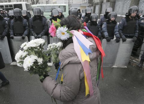 A pro-EU activist offers flowers to police officers at the presidential office in Kiev on December 8.