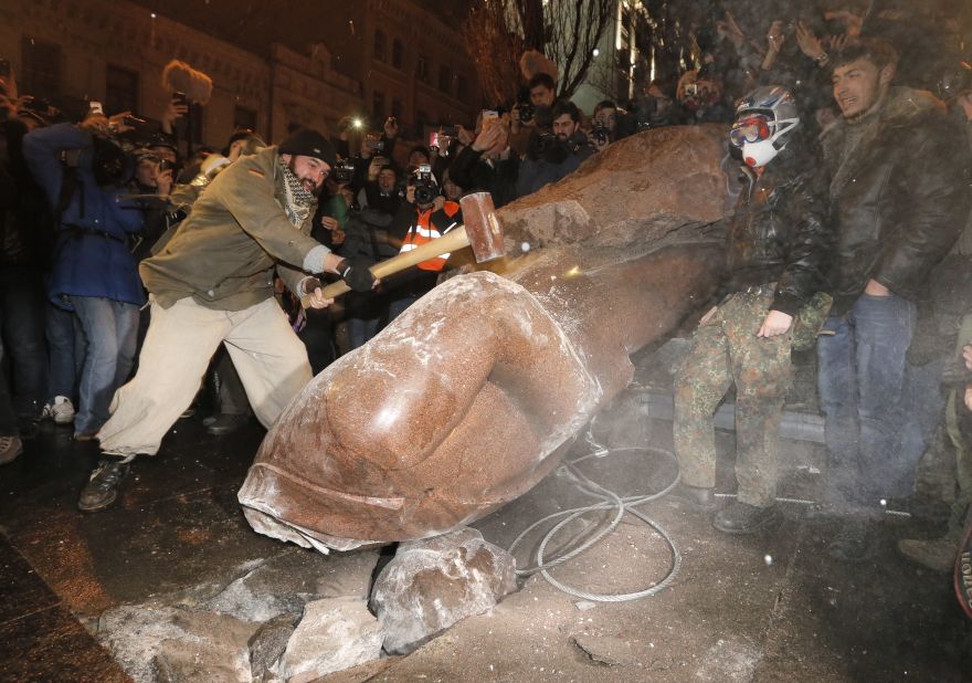 A protester in Kiev slams a toppled monument of Vladimir Lenin on December 8.