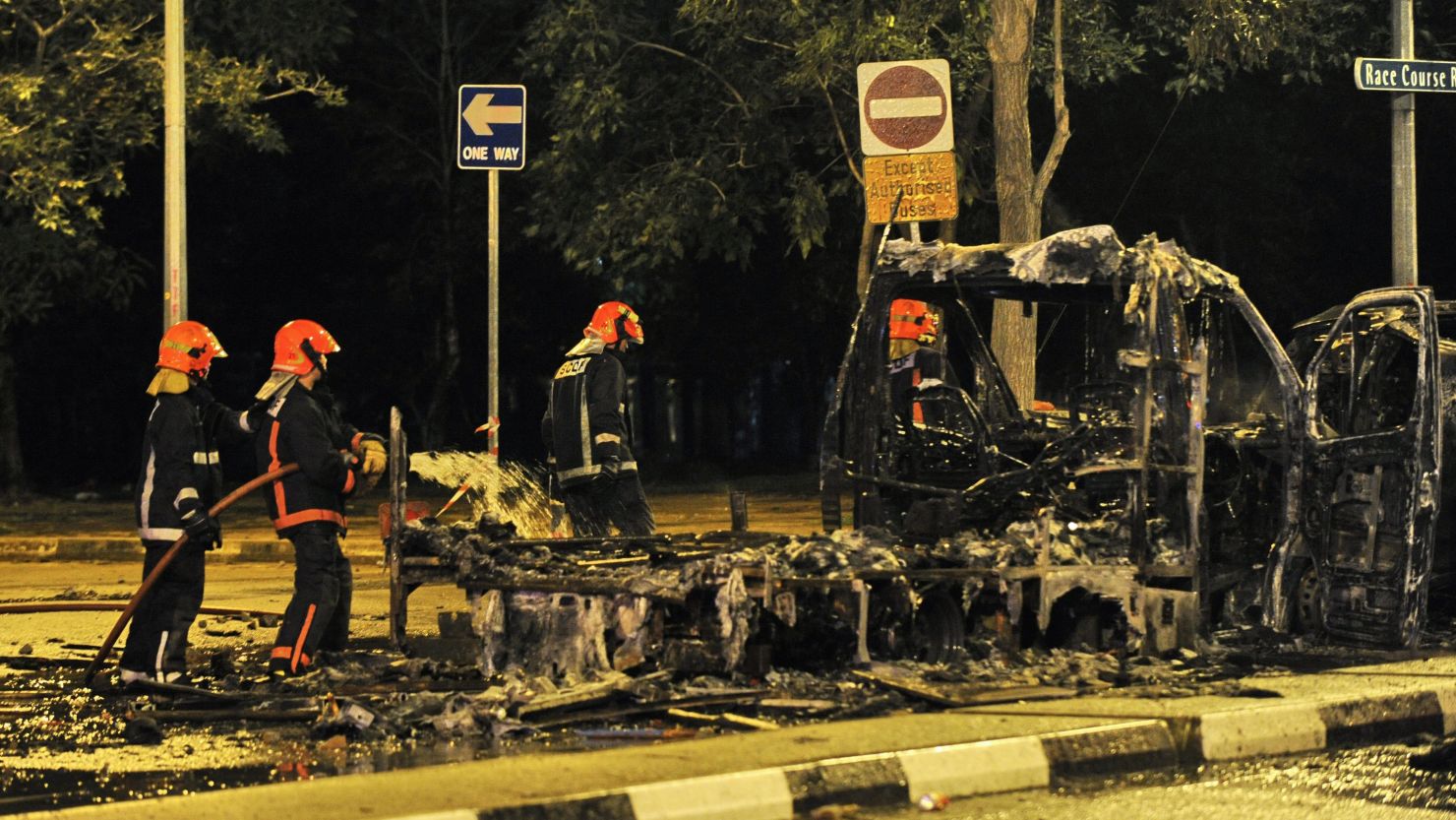 Firemen douse a charred ambulance in the early hours of December 9, 2013, after a fatal traffic accident sparked a riot in Singapore's Little India district.