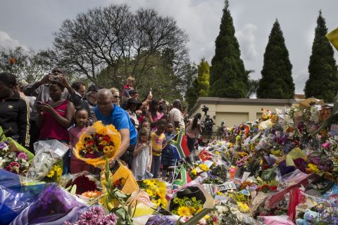 Crowds of people pay tribute to Mandela outside his Johannesburg home on December 7.