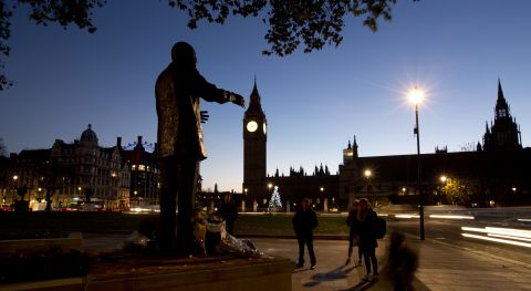 Early morning commuters stand in silence beside a statue of Mandela on December 6 in Parliament Square in London.