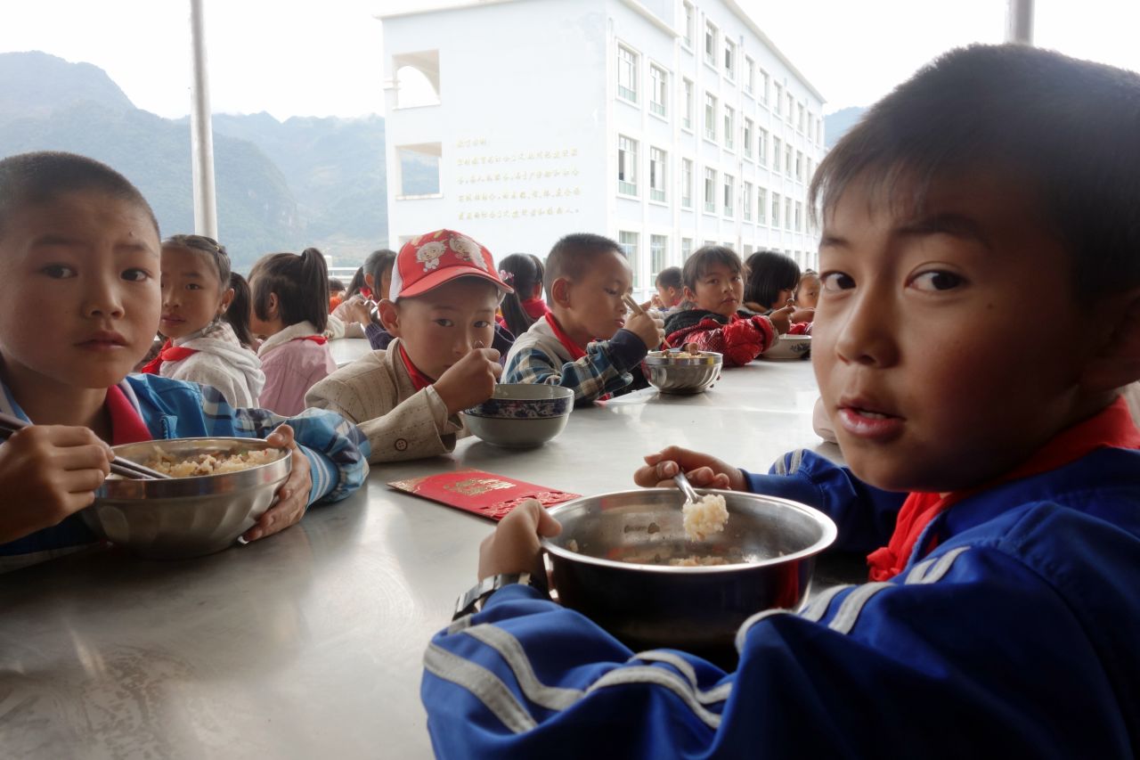 The children eat lunch at an outside cafeteria.