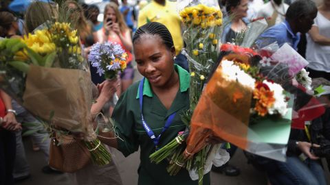 A groundskeeper collects flowers left by visitors at Mandela's home in Johannesburg on December 9.