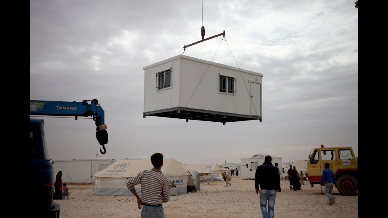 Refugees watch a new trailer being placed in the Zaatari camp on December 3.