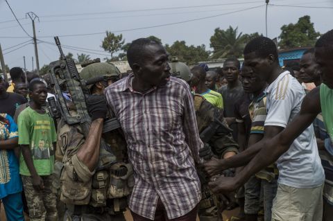 People gather around an alleged ex-Seleka rebel as he is arrested by French soldiers in Bangui on December 9.