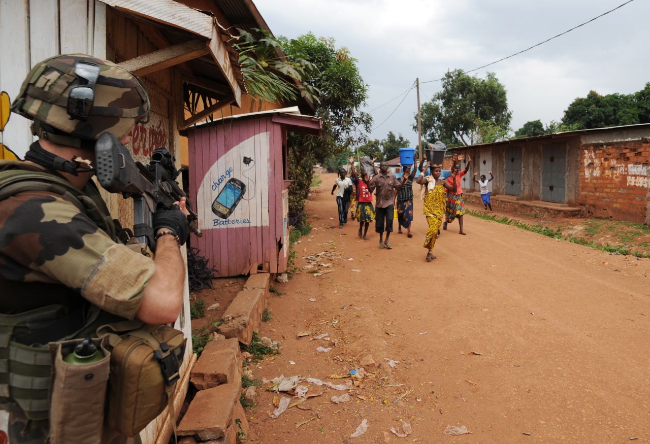 People walk by a French soldier standing guard during a disarmament operation in Bangui on December 9.