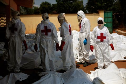 Red Cross employees stand amid dozens of bodies at the morgue in Bangui on December 8.