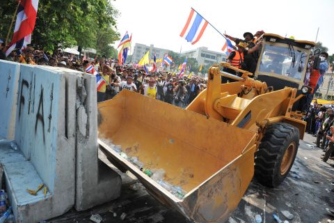 Protesters use a bulldozzer to clear a police barricade blocking an access road leading to Government House during a large anti-government rally on December 9.