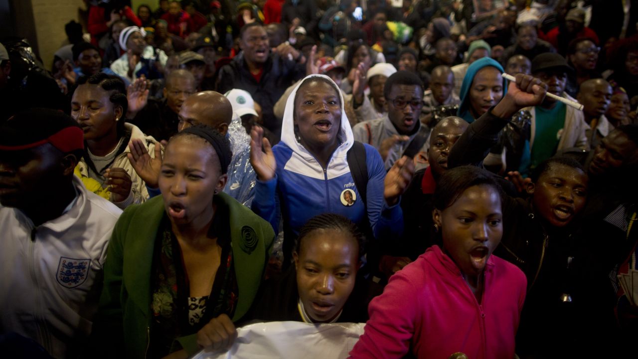 Mourners sing as they take shelter from the rain in the hallways of FNB Stadium.