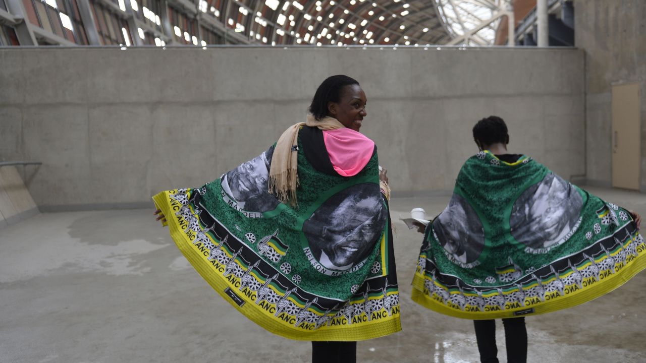 Women draped in flags printed with Mandela's face arrive at FNB Stadium.
