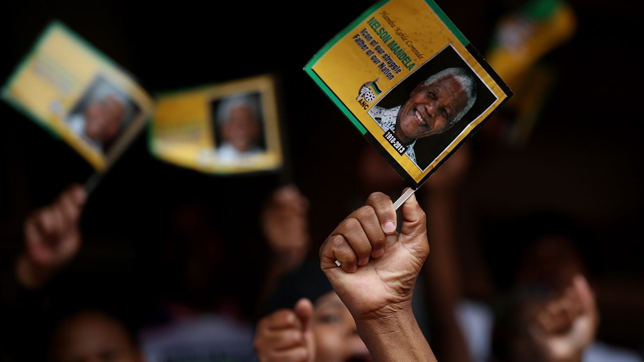 Mourners wave flags at a telecast of the memorial service at Ellis Park in Johannesburg.
