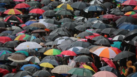 People take shelter under umbrellas at FNB Stadium.
