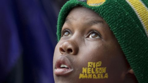 A boy looks up during the memorial service at FNB Stadium. He has "RIP Nelson Mandela" painted on his face.