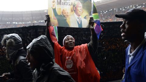 A man displays a sign with pictures of Mandela during the memorial service.