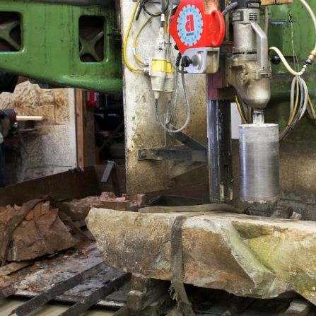 A machine cores a hole into the base of the curling stone, in this case the common green stone, and a mold of separate granite is added to make an even higher quality product.