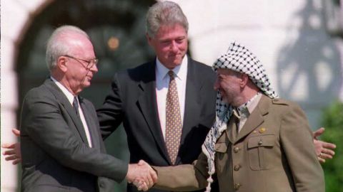 U.S. President Bill Clinton stands between PLO leader Yasser Arafat and Israeli Prime Minister Yitzahk Rabin as the two shake hands on October 25, 1995.   Rabin and Arafat shook hands for the first time after Israel and the PLO signed a historic agreement on Palestinian autonomy in the occupied territories.