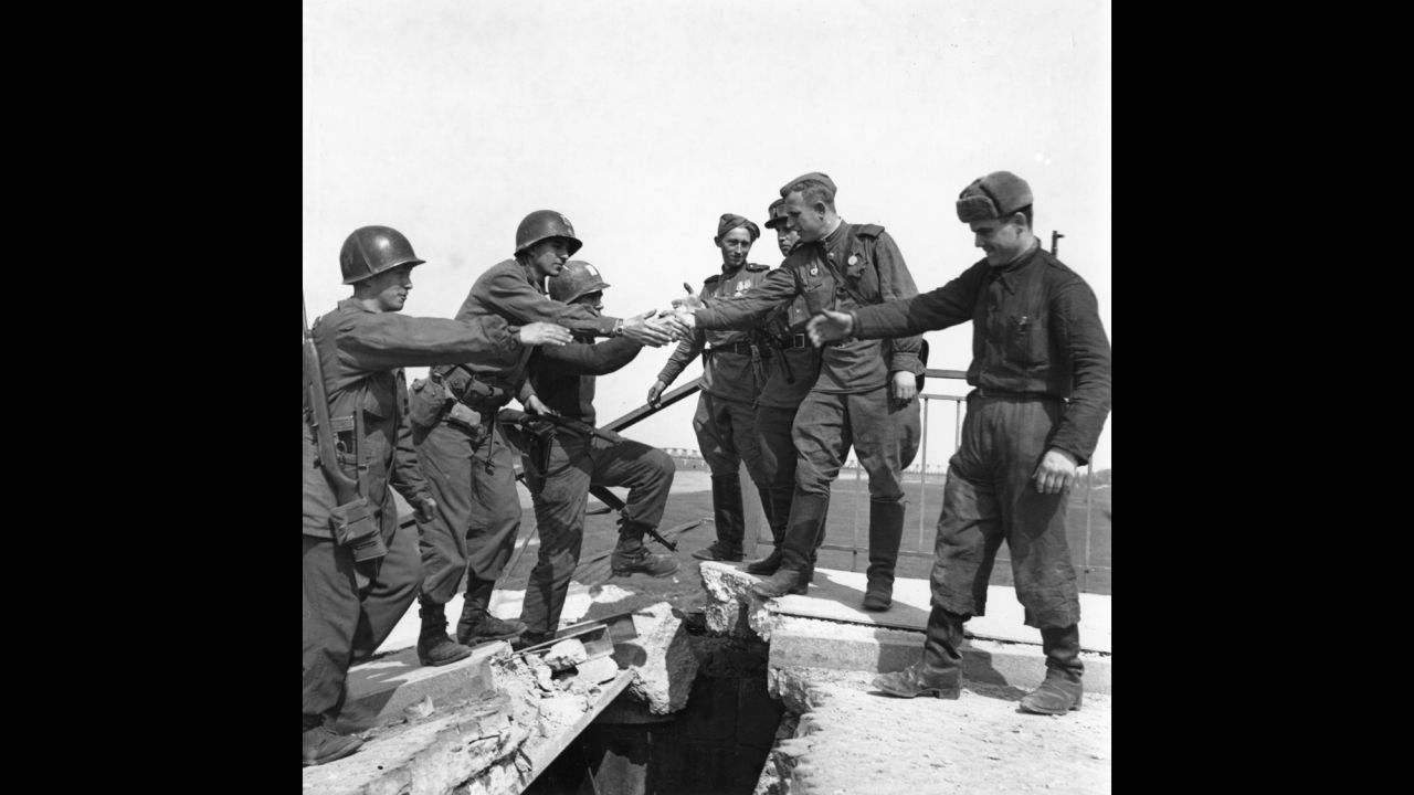 Near the end of World War II, U.S. infantrymen shake hands with Russian soldiers on the broken bridge over the Elbe River after the link-up at Torgau, Germany, on April 27, 1945.