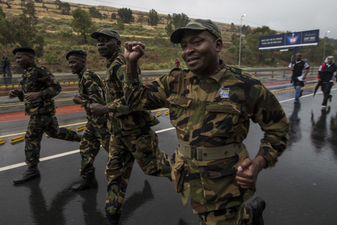 Former members of the armed wing of the African National Congress run through the streets on their way to the memorial service.