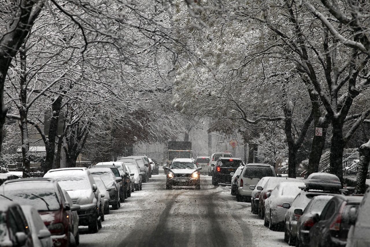 A car drives up a snow-covered street in Brooklyn, New York, on December 10.