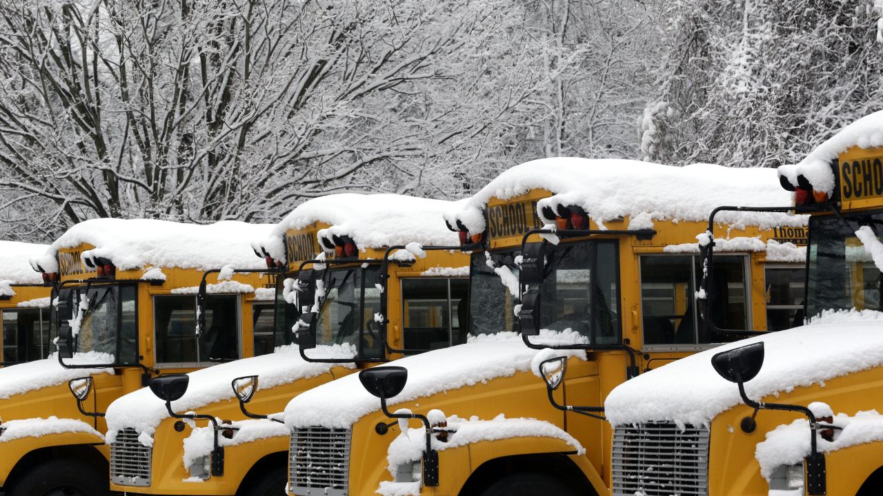 Snow covers buses for the Baltimore County Public Schools in Towson, Maryland, on Tuesday, December 10. Snow and ice snarled travel across parts of the United States, hitting major airline hubs in the Northeast.