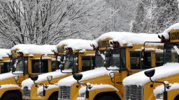 Baltimore County Public School buses sit covered in snow in a parking lot in Towson, Maryland, on Tuesday, December 10.
