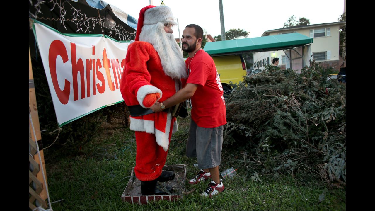 Anthony Martinez, owner of a Miami Christmas tree lot, adjusts the outfit on a Santa Claus mannequin while waiting for customers December 9.