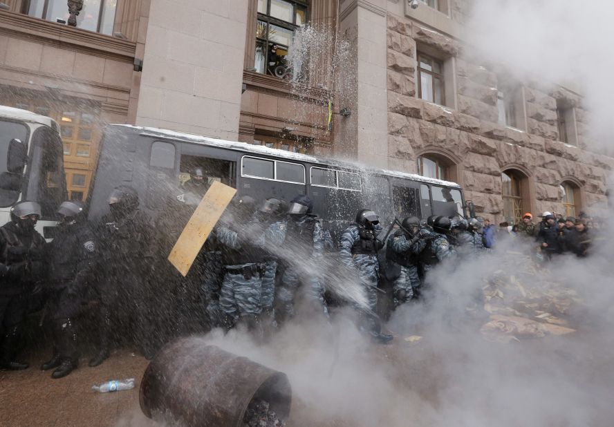 Riot police officers block the entrance of Kiev's City Hall as protesters pour water from windows and throw smoke grenades at them on December 11.