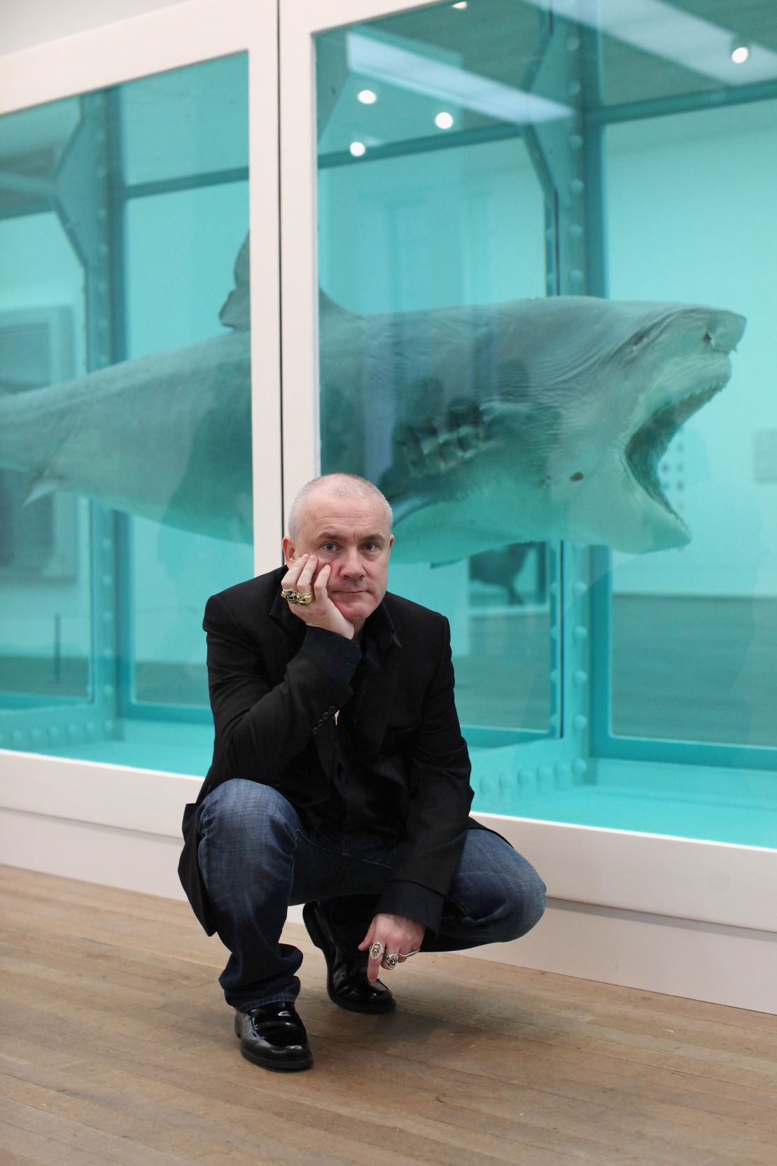 Hirst poses in front of "The Physical Impossibility of Death in the Mind of Someone Living" in London's Tate Modern art gallery on April 2, 2012.