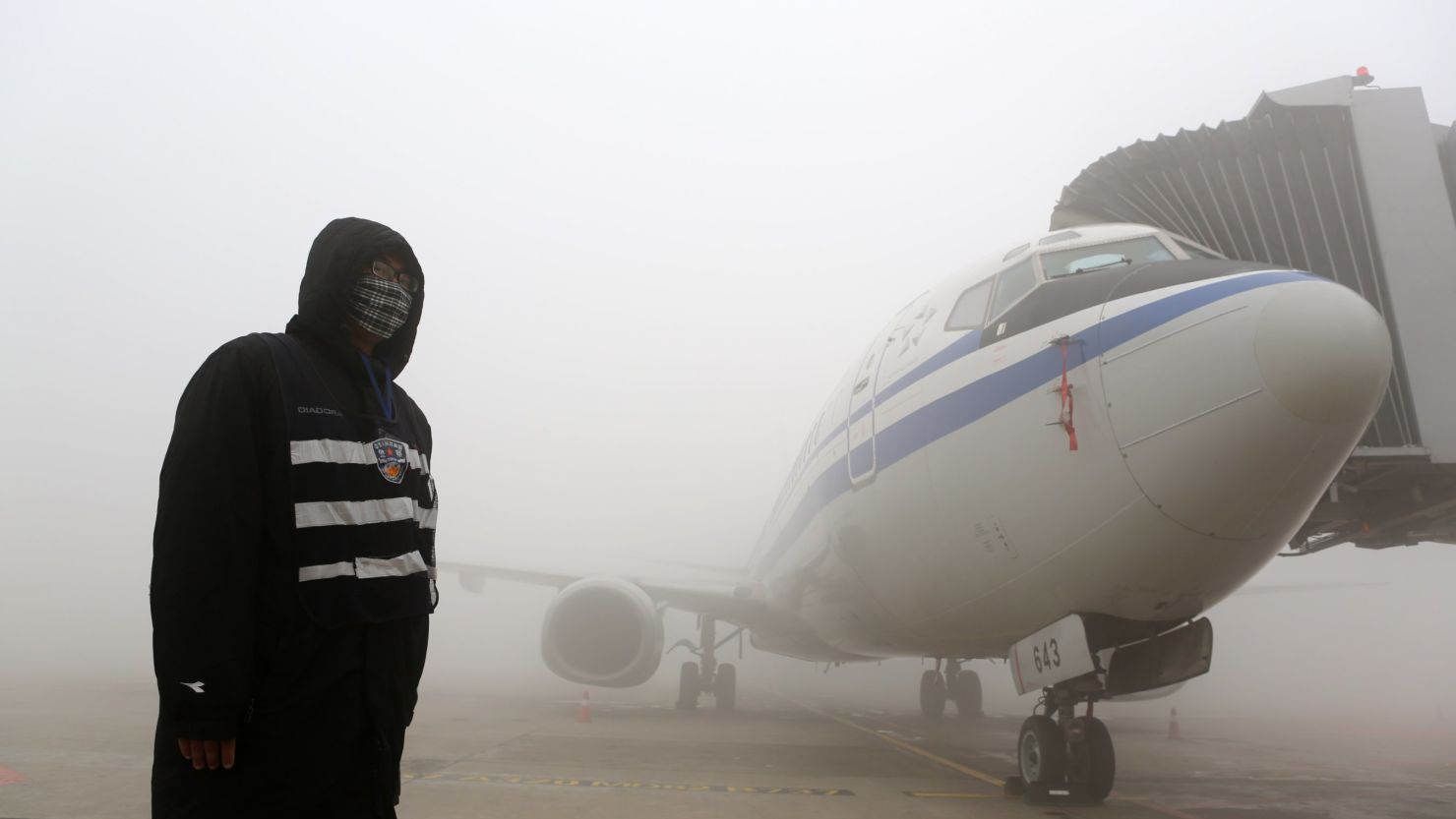A man stands next to an airplane in heavy smog in Harbin, northeast China's Heilongjiang province, on October 21, 2013. 