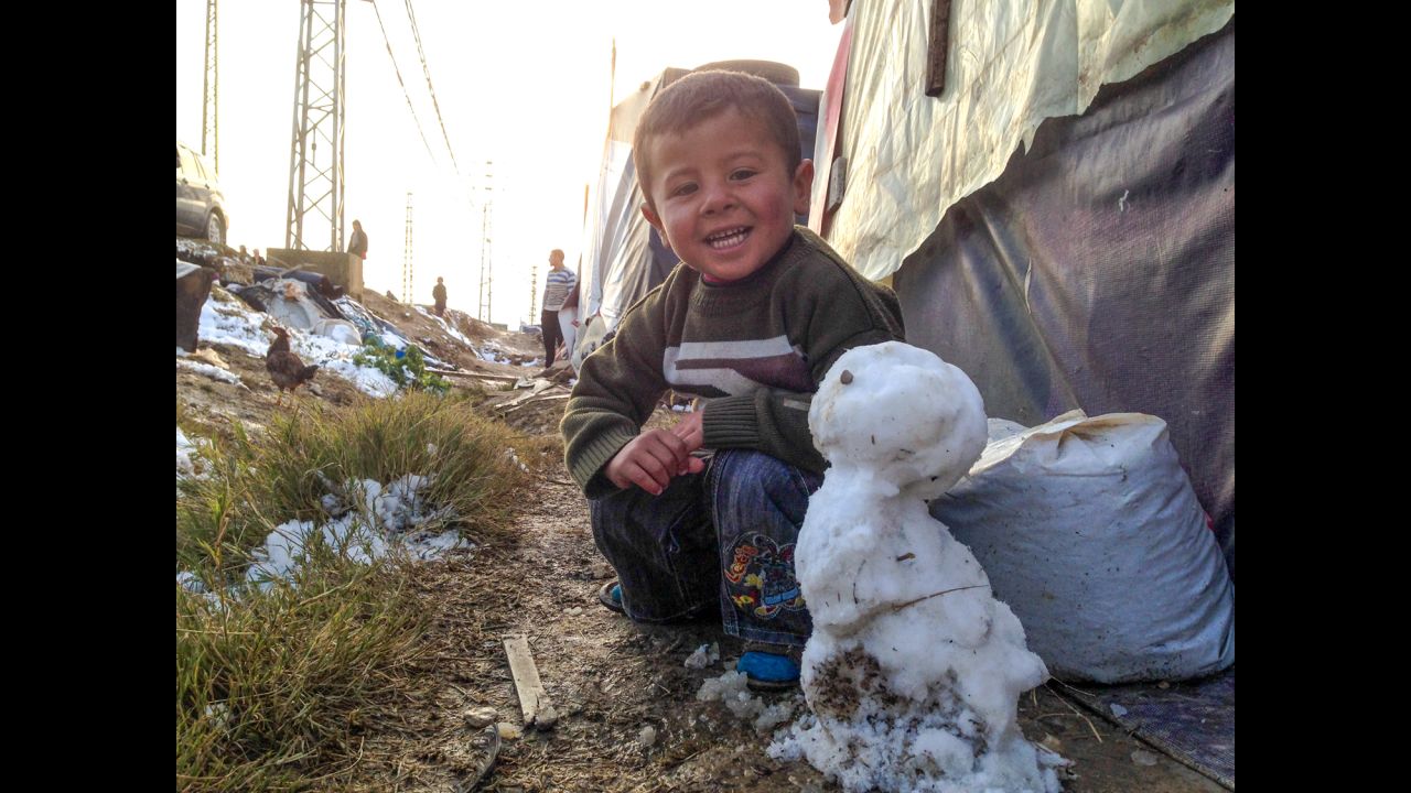 A Syrian boy shows off his snowman at a refugee camp in the Bekaa Valley on December 12.