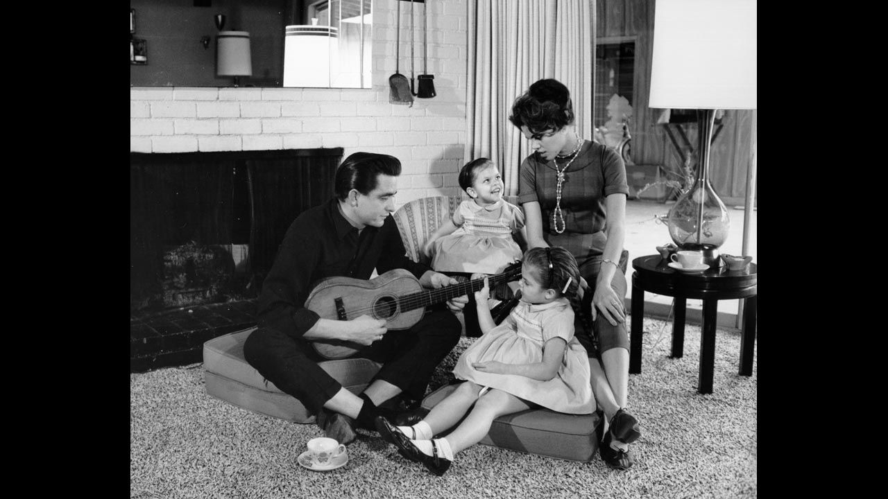 Cash holds a guitar as his then-wife Vivian Liberto and daughters Rosanne and Kathy look on in 1957. 