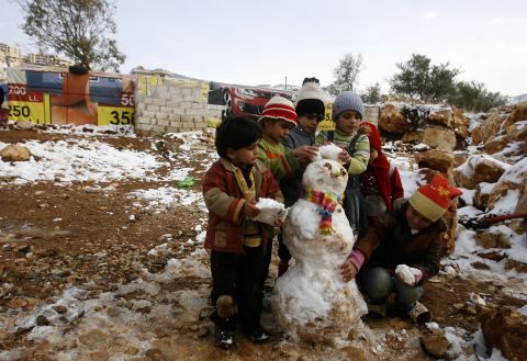 Young Syrian refugees build a snowman following a storm in the Lebanese village of Baaloul on Thursday, December 12.