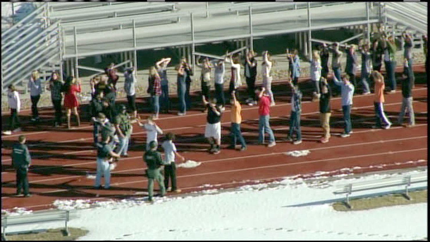 Persons evacuated from Arapahoe High School in Centenial, Colorado, walk on the school's track after a shooting at the school.