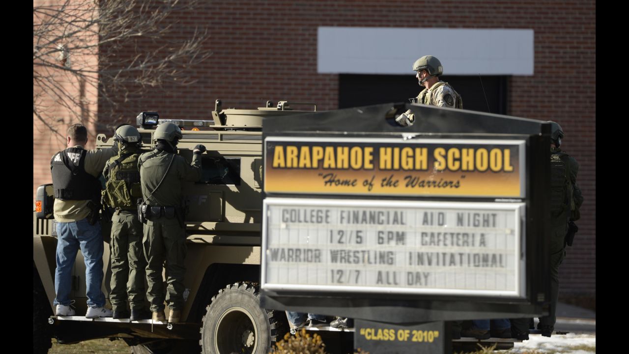 Law enforcement personnel arrive at the high school in a military-style vehicle. 