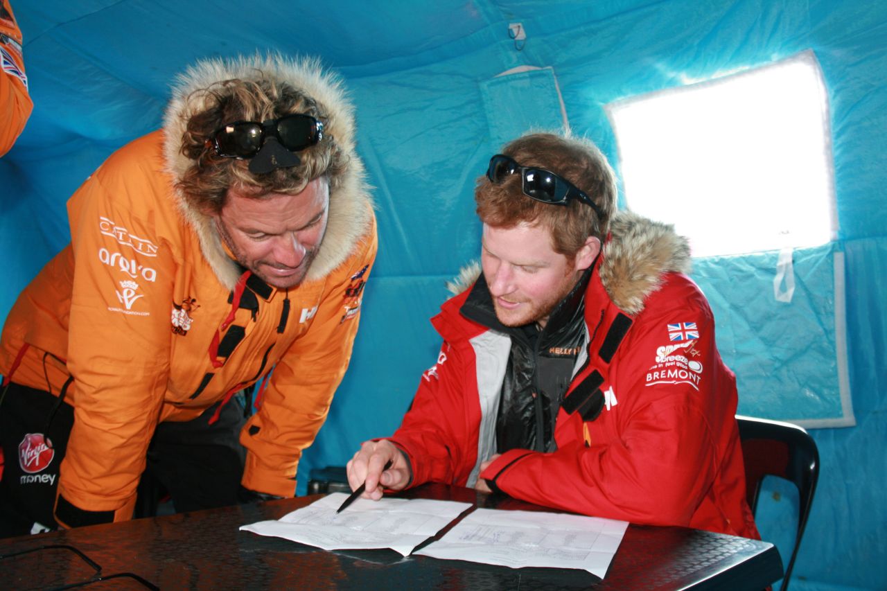 Prince Harry, right, and Dominic West make notes on the weight of each participant and kit during preparations in Novo.