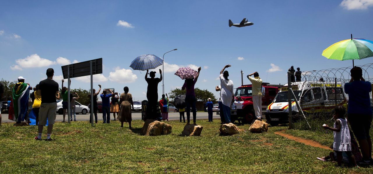 People wave at the aircraft carrying the casket of Mandela as it takes off from Waterkloof air base on the outskirts of Pretoria, South Africa.