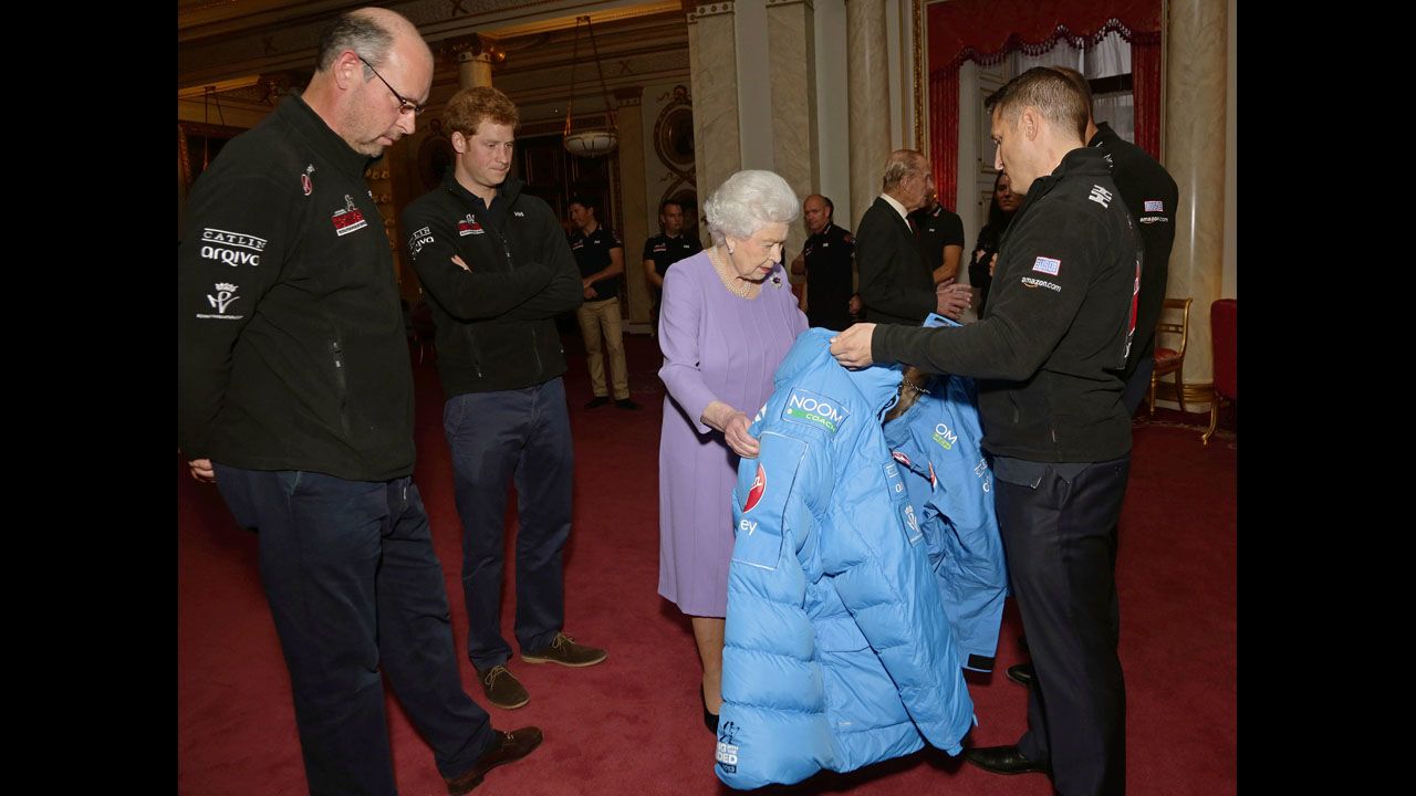 Britain's Queen Elizabeth II examines a jacket presented by a member of Team USA as her grandson looks on during a reception at Buckingham Palace in London on November 13 ahead of the Walking With the Wounded South Pole Allied Challenge.